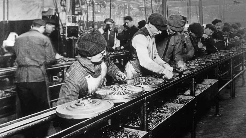 Fotografía de 1913 de obreros montando volantes de inercia (magneto) en una línea de montaje de Ford en la planta de Highland Park. Foto histórica.