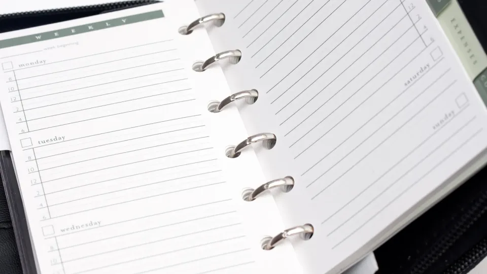Agenda de anillas abierta por una página semanal en blanco, con casillas y líneas para planificar cada día. Foto genérica de una agenda; no ilustra el estudio concreto.